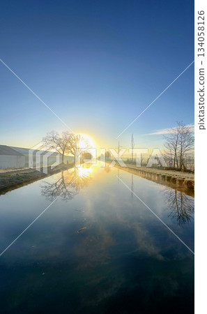 A Serene and Beautiful Reflection of a Sunrise Over a Tranquil Waterway in Nature 134058126