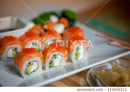 Salmon sushi set. Sushi roll Philadelphia with red fish, salmon, red caviar. Roll with soft avocado and cream cheese under a layer of massago caviar. Classic sushi. Food background. 134058211
