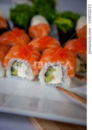 Salmon sushi set. Sushi roll Philadelphia with red fish, salmon, red caviar. Roll with soft avocado and cream cheese under a layer of massago caviar. Classic sushi. Food background. Salmon sushi set. Sushi roll Philadelphia with red fish, salmon, red caviar. Roll with soft avocado and cream cheese under a layer of massago caviar. Classic sushi. Food background. 134058213