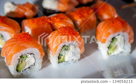 Salmon sushi set. Sushi roll Philadelphia with red fish, salmon, red caviar. Roll with soft avocado and cream cheese under a layer of massago caviar. Classic sushi. Food background. Salmon sushi set. Sushi roll Philadelphia with red fish, salmon, red caviar. Roll with soft avocado and cream cheese under a layer of massago caviar. Classic sushi. Food background. 134058215