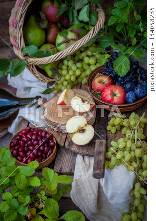 Autumn still life. Fruits and berries. Apples, grapes, strawberries, plums on a wooden table. Country style. Idle healthy vitamin food. Fruit harvest. Old knife. An apple in a basket. Autumn still life. Fruits and berries. Apples, grapes, strawberries, plums on a wooden table. Country style. Idle healthy vitamin food. Fruit harvest. Old knife. An apple in a basket. 134058235