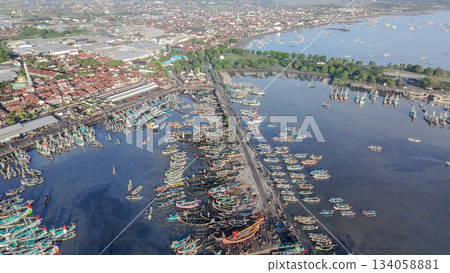 Aerial view of busy traditional fishing port in Muncar, Indonesia, featuring hundreds of boats and a sprawling coastal town. Aerial view of busy traditional fishing port in Muncar, Indonesia, featuring hundreds of boats and a sprawling coastal town. 134058881