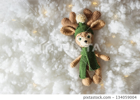 Handmade Knitted Christmas Reindeer Doll with Fairy Lights on Fluffy White Background 134059004