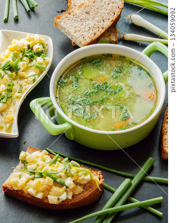 Homemade warm healthy chicken broth with boiled veggies and egg salad sandwiches for cold season. Homemade warm healthy chicken broth with boiled veggies and egg salad sandwiches for cold season. 134059092