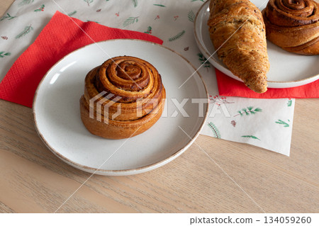 Cinnamon roll and freshly baked pastries on cozy table setting. Christmas mood Cinnamon roll and freshly baked pastries on cozy table setting. Christmas mood 134059260