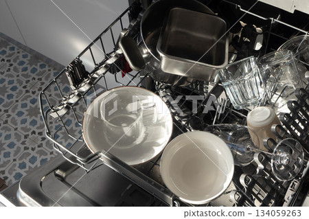 Open dishwasher with clean dishes in morning sunlight. Cleaning routines, sustainable living Open dishwasher with clean dishes in morning sunlight. Cleaning routines, sustainable living 134059263