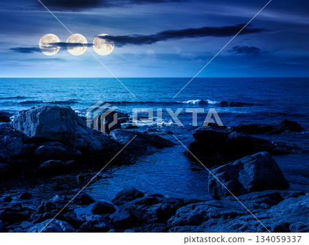 rocky shore of the sea coast under blue sky at night. beautiful view of coastal scene in full moon light. resort scenery during vacation season in summer. backdrop for fiction art or mystery concepts 134059337