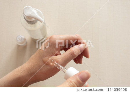 Serum application on hand with dropper, neutral minimal skincare concept Serum application on hand with dropper, neutral minimal skincare concept 134059408