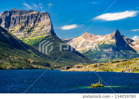 Wild Goose Island sits in blue waters of Saint Mary Lake in Glacier National Park, Montana, USA. Scenic landscape features majestic peaks and pine trees in UNESCO World Heritage site Wild Goose Island sits in blue waters of Saint Mary Lake in Glacier National Park, Montana, USA. Scenic landscape features majestic peaks and pine trees in UNESCO World Heritage site 134059760