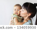 Mother gently kissing baby on cheek, capturing tender and emotional family moment 134059930