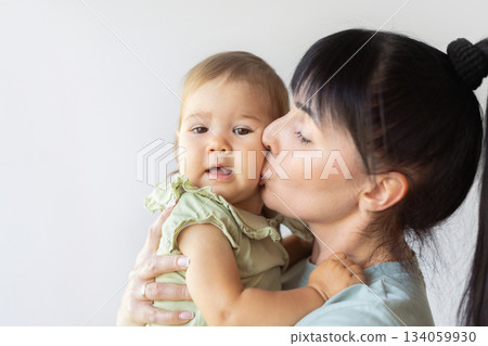 Mother gently kissing baby on cheek, capturing tender and emotional family moment Mother gently kissing baby on cheek, capturing tender and emotional family moment 134059930