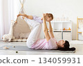 Mother lifting baby above her legs during playful exercise on yoga mat 134059931