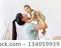 Loving mother lifting her baby playfully, creating joyful bonding moment at home 134059939