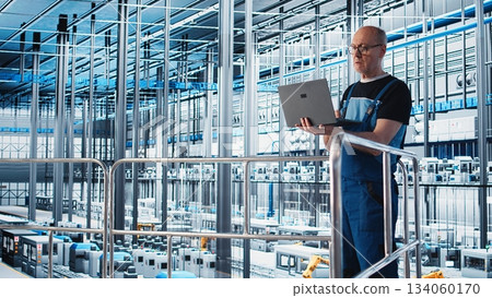 Industry 4.0 industrial plant expert automating robotic manufacturing machinery using device. Elderly employee implementing artificial intelligence in smart factory using notebook, camera A 134060170