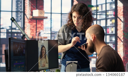 Team of experts work on social media content and video editing with dual monitors, AI tools and color grading software in a modern studio, enhancing visibility, engagement and reach. Camera B. 134060187