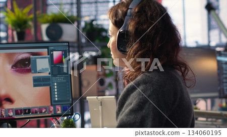 Woman editor using color grading on retouching software at the agency, working on professional high quality photos. Designer working with editing interface and tools for media content. Camera B. 134060195