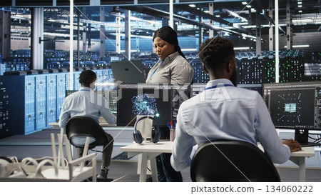 Data center computer scientists use node tree programming to identify equipment performance issues. Server farm employees review data analysis graphs to minimize infrastructure failures, camera A 134060222