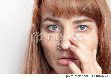 Woman smears dark circles under her eyes with concealer finger close up photo 134060271