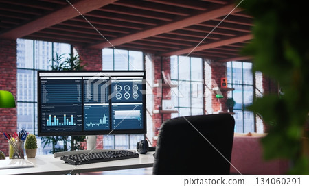Monitor showcases business trends and targeted marketing development, SEO tools and analytics in an empty loft apartment with a spacious modern interior and a minimalist desk setup. 134060291