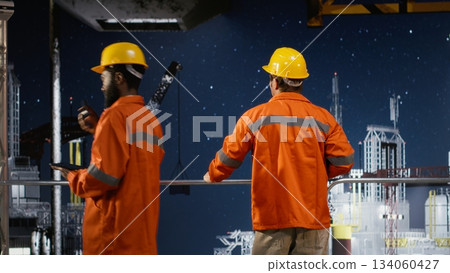 Worker in hard hat conducts system inspections on offshore drilling rig from industrial platform, focusing on marine fossil fuel extraction and monitoring practices for oil production. Worker in hard hat conducts system inspections on offshore drilling rig from industrial platform, focusing on marine fossil fuel extraction and monitoring practices for oil production. 134060427