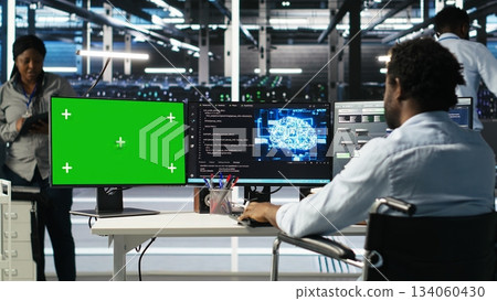 Data center worker with paraplegia using green screen PC to apply node tree programming. Server hub admin with disability uses visual programming on mockup computer to identify data patterns, camera B 134060430