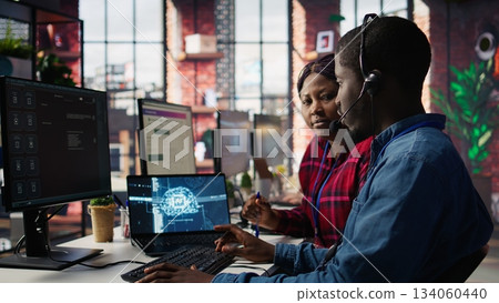 Call center agents using artificial intelligence tech to provide step by step guidance to customers. Customer center coworkers using AI technology to walk clients through technical solutions, camera B 134060440