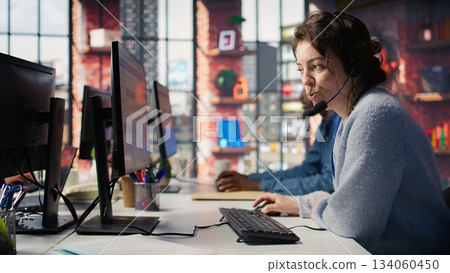 Joyous call center agent providing step by step guidance to resolve customers concerns. Happy customer center worker diagnosing problems, walking clients through technical solutions, camera B 134060450