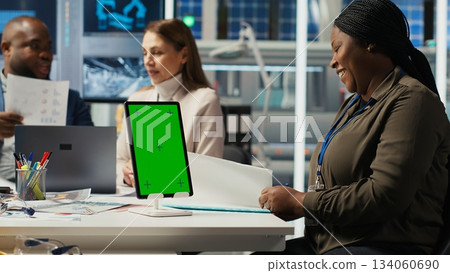Managers in office reviewing solar technology reports on isolated screen tablet. Shareholders using chroma key device, discussing investment opportunities in green energy production, camera B 134060690