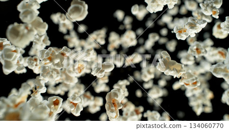 Dynamic macro shot of flying popcorn pieces against a black background. Crisp detail and motion captured in a dramatic, high-contrast composition. Perfect for advertising or creative design. Dynamic macro shot of flying popcorn pieces against a black background. Crisp detail and motion captured in a dramatic, high-contrast composition. Perfect for advertising or creative design. 134060770