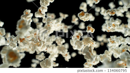 Dynamic macro shot of flying popcorn pieces against a black background. Crisp detail and motion captured in a dramatic, high contrast composition. Perfect for advertising or creative design. 134060795
