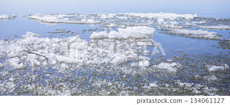 Ice fragments floating on calm water surface in serene natural environment Spring banner Ice fragments floating on calm water surface in serene natural environment Spring banner 134061127
