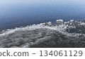 Ice fragments along tranquil water's edge reflecting clear blue sky 134061129