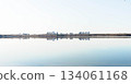 Serene landscape with calm water reflecting city skyline and blue sky 134061168