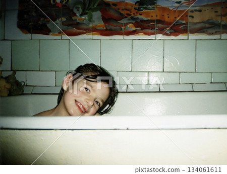 Vintage portrait of a girl child bathing in a bathtub. The child is smiling. Retro 1999. 134061611