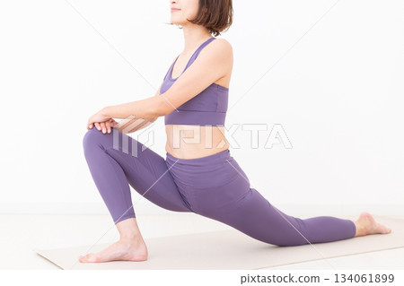Middle-aged woman in yoga wear stretching at home Middle-aged woman in yoga wear stretching at home 134061899