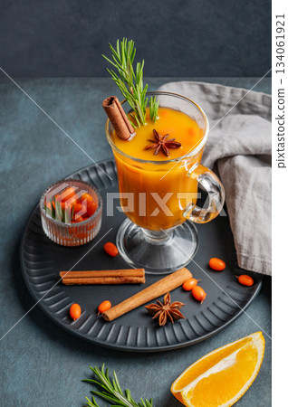 Sea buckthorn herbal tea in a glass on a black plate on a dark background with berries 134061921