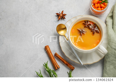 Sea buckthorn herbal tea in a cup on a light background with spices and berries. Sea buckthorn herbal tea in a cup on a light background with spices and berries. 134061924