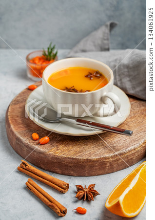 Sea buckthorn herbal tea in a cup on a wooden board on a light background 134061925