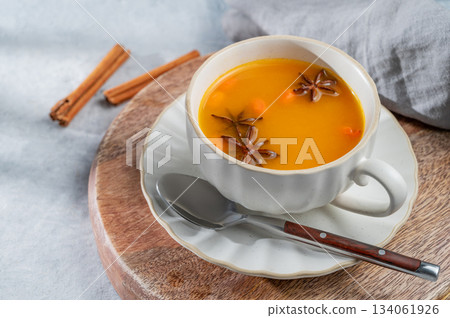 Sea buckthorn herbal tea in a cup on a wooden board on a light background with spices Sea buckthorn herbal tea in a cup on a wooden board on a light background with spices 134061926