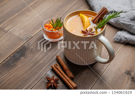 Sea buckthorn herbal tea in a cup on a wooden background with spices, berries and napkin Sea buckthorn herbal tea in a cup on a wooden background with spices, berries and napkin 134061929