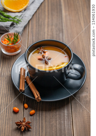 Sea buckthorn herbal tea in a black cup on a wooden background with spices Sea buckthorn herbal tea in a black cup on a wooden background with spices 134061930