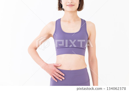 一位中年女性身穿瑜珈服,露出纖細的腹部 一位中年女性身穿瑜珈服,露出纖細的腹部 134062378