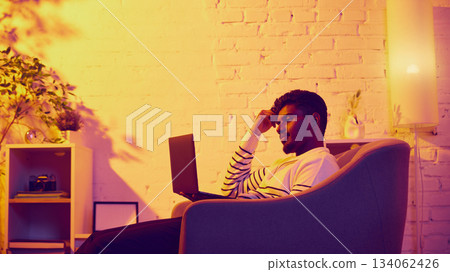 Man relaxing with laptop in cozy warm room Man relaxing with laptop in cozy warm room 134062426