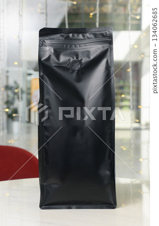 Vertical black matte coffee bag with flap on cafe table Vertical black matte coffee bag with flap on cafe table 134062685