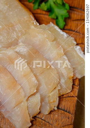 Sliced fillet of white smoked fish on a wooden board Sliced fillet of white smoked fish on a wooden board 134062697