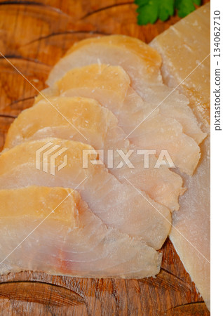 Sliced smoked or dried fish fillet on a wooden board with tomatoes 134062710