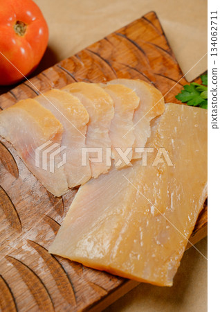 Sliced smoked or dried fish fillet on a wooden board with tomatoes Sliced smoked or dried fish fillet on a wooden board with tomatoes 134062711