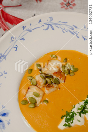 Pumpkin cream soup with seeds, cream, and parsley on a plate Pumpkin cream soup with seeds, cream, and parsley on a plate 134062721