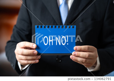 Businessman holding a notebook with the words Oh no. Businessman holding a notebook with the words Oh no. 134062791