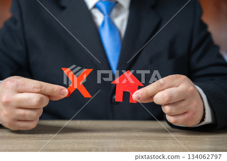 Businessman holding a prohibition sign over a house Businessman holding a prohibition sign over a house 134062797
